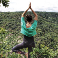 Schwarzweiß-Foto einer lachenden, dunkelhaarigen Frau, die einen Rucksack trägt